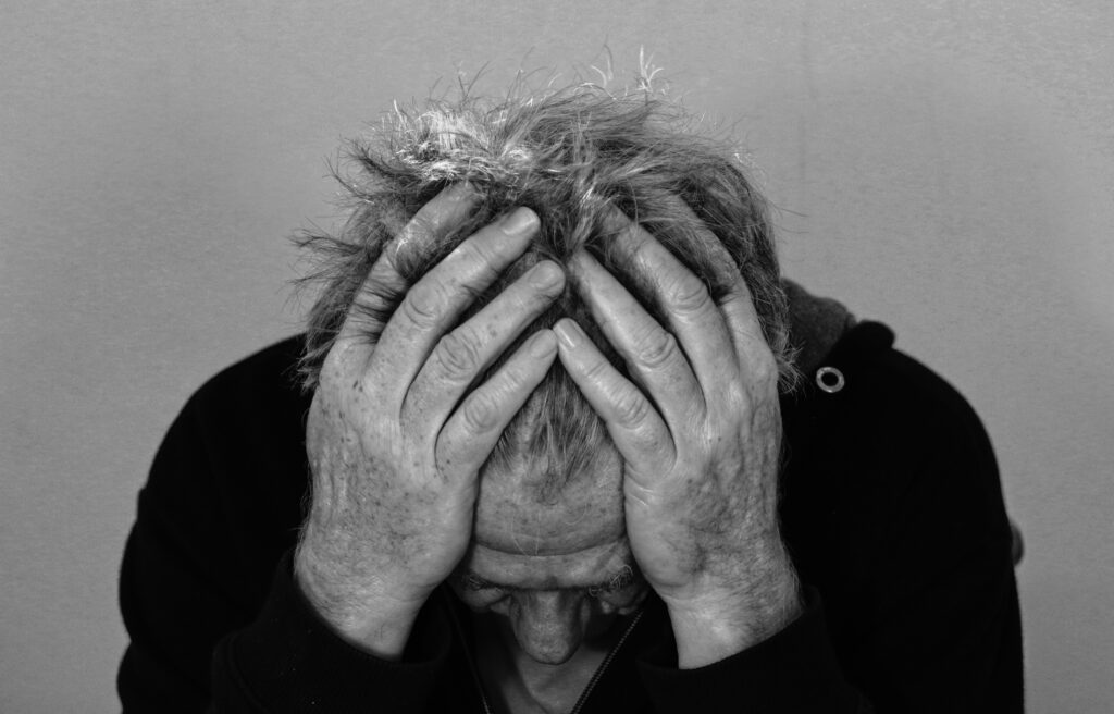 Stressed older man holding head in hands – illustrating emotional burnout and fatigue.